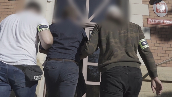 Dwaj nieumundurowani policjanci doprowadzają zatrzymanego do prokuratury okręgowej.
