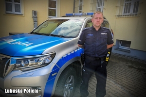 Policjant stoi przy radiowozie.