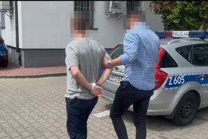 policjant idzie z zatrzymanym.