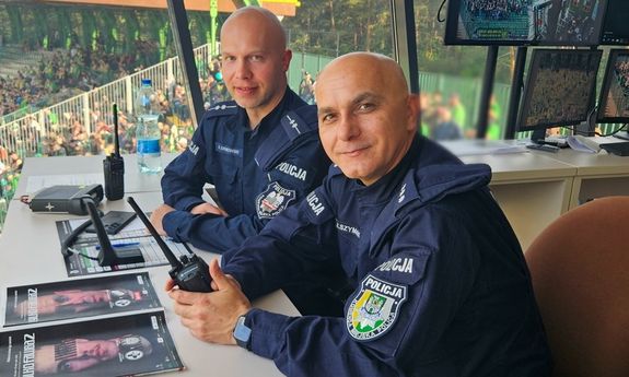 dwóch policjantów siedzi przy biurku.