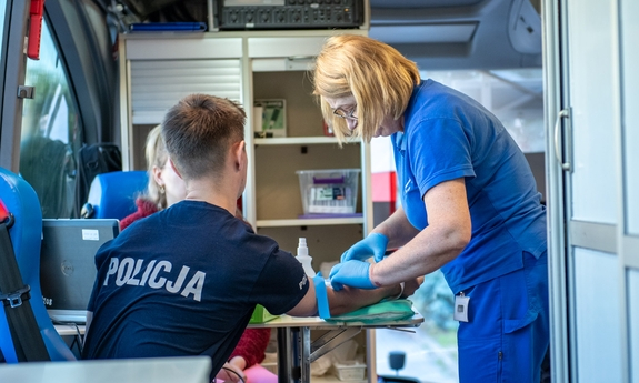 Policjant w mobilnym punkcie poboru krwi i pielęgniarka.