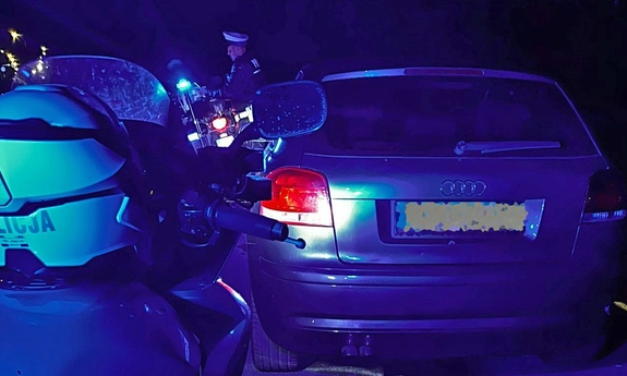 Zatrzymany przez policjantów samochód osobowy. Obok policjant na motocyklu.
