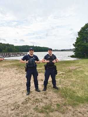 Dwaj policjanci stoją na brzegu zbiornika wodnego.