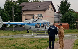 Policjant z drugim mężczyzna w tle widać policyjny śmigłowiec.