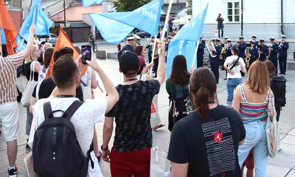 tłum ludzi stoi przed orkiestrą policyjną.