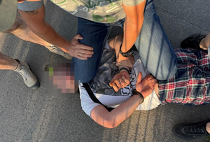 Policjant podczas zatrzymania mężczyzny, który leży na ziemi.