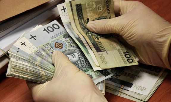 Dłonie w rękawiczkach i banknoty.