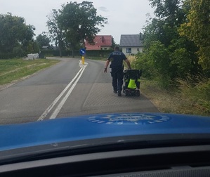 policjant prowadzi wózek inwalidzki.