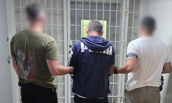 Dwaj policjanci prowadzą zatrzymanego mężczyznę.