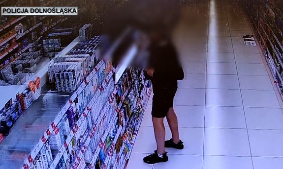 Stop klatka z materiału filmowego, na którym widać jak mężczyzna dopuszcza się kradzieży.