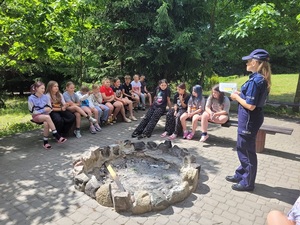 Policjantka rozmawia z grupą dzieci przebywających na koloniach.