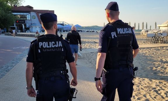dwóch policjantów idzie wzdłuż plaży.