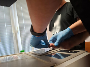 policjant pobiera odciski palców zatrzymanemu.