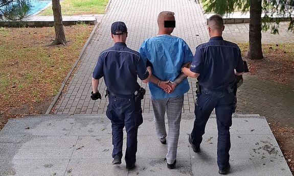 Dwaj policjanci prowadzą zatrzymanego.