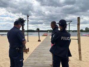 Policjanci rozmawiają z pracownikiem wypożyczalni sprzętu wodnego.