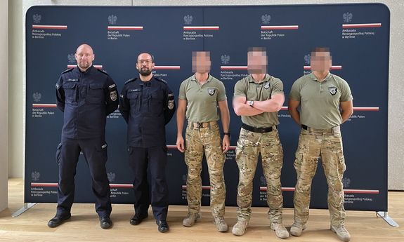 Trzej kontrterroryści i dwaj policjanci pozują do zdjęcia. W tle ścianka Ambasady RP w Berlinie.