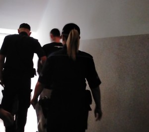 policjanci schodzą po schodach z zatrzymanym.