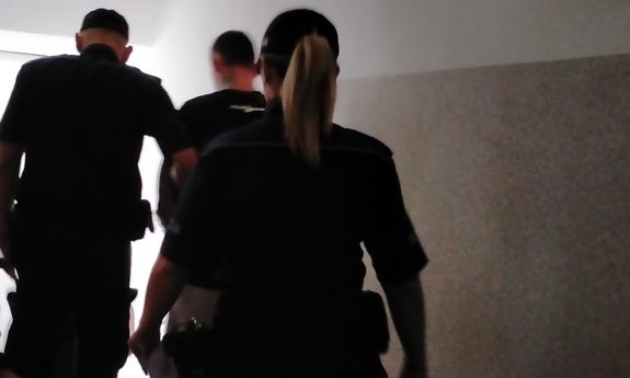 policjanci schodzą po schodach z zatrzymanym.