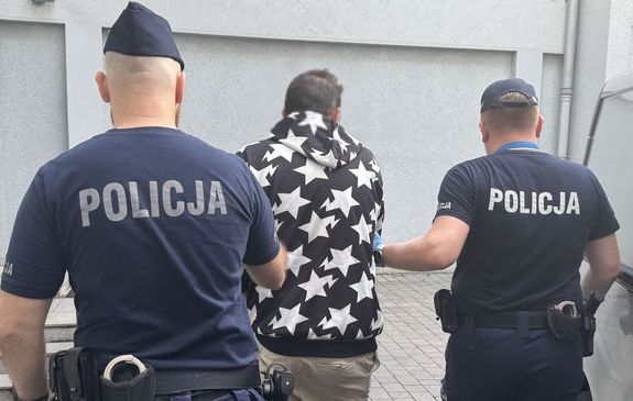 Dwaj policjanci prowadzą zatrzymanego.