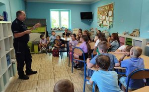 Policjant z grupą dzieci podczas spotkania profilaktycznego.