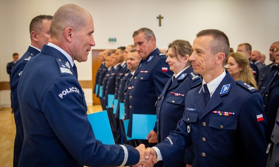 I zastępca komendanta głównego Policji wręcza podziękowanie policjantowi.