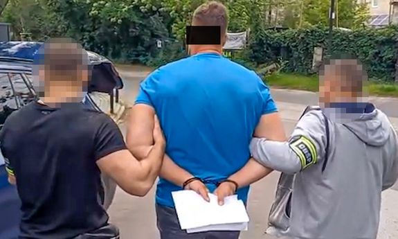 policjanci idą z zatrzymanym.