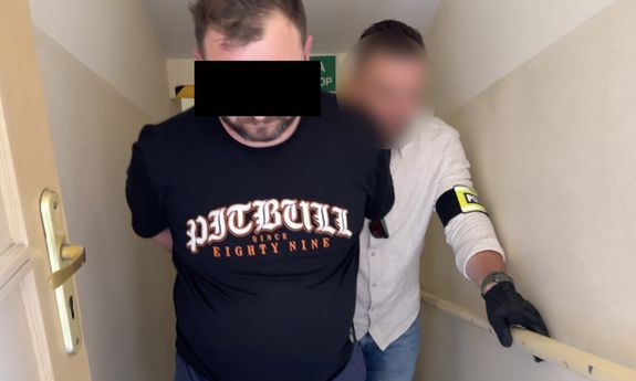 policjant idzie z zatrzymanym.