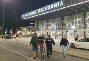 Policjanci wyprowadzają zatrzymanego mężczyznę z dworca Warszawa Wschodnia.