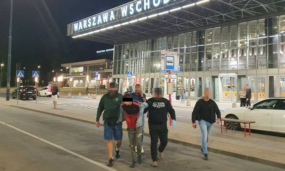 Policjanci wyprowadzają zatrzymanego mężczyznę z dworca Warszawa Wschodnia.