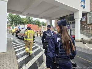 Policjantka i policjant idą drogą za strażakami.