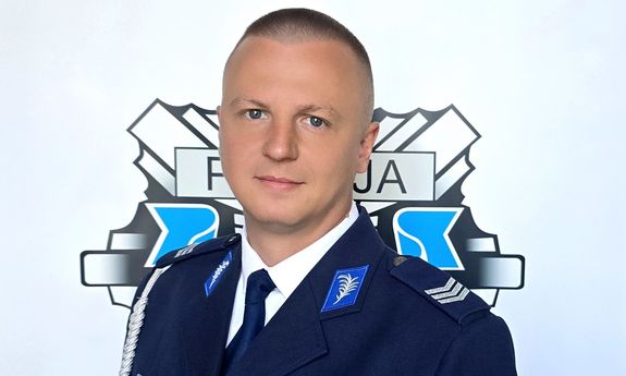 Policjant w mundurze pozuje do zdjęcia.