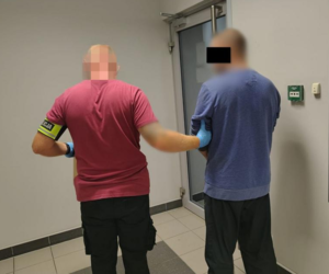 Policjant prowadzi zatrzymanego.