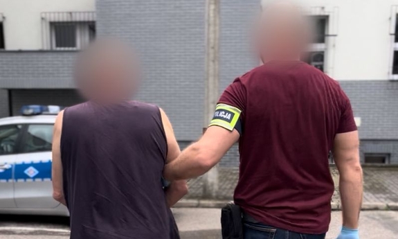 Policjant prowadzi zatrzymanego.