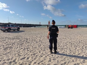 Policjant stoi na plaży.