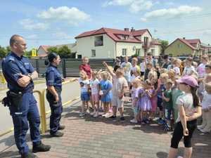 Para policjantów rozmawia z dziećmi podczas spotkania profilaktycznego.