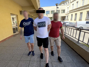 Dwaj policjanci prowadzą zatrzymanego.