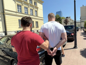 Policjant prowadzi zatrzymanego.