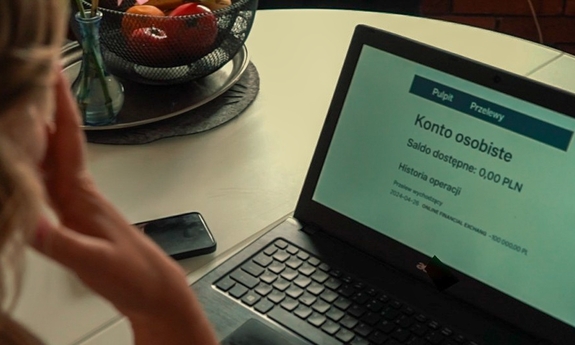 Kobieta siedzi przed ekranem laptopa.