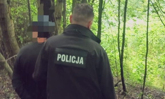Policjant z zatrzymanym mężczyzną w lesie.