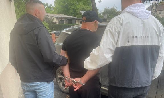 Na zdjęciu widocznych dwóch nieumundurowanych policjantów prowadzących zatrzymanego.
