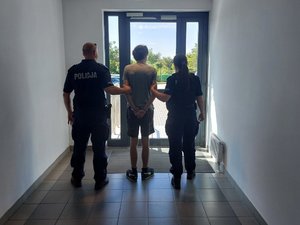 dwóch policjantów stoi z zatrzymanym.