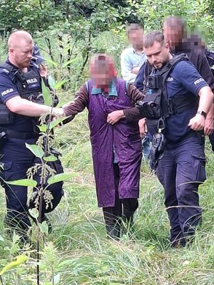 Policjanci prowadzą odnalezioną starszą panią.