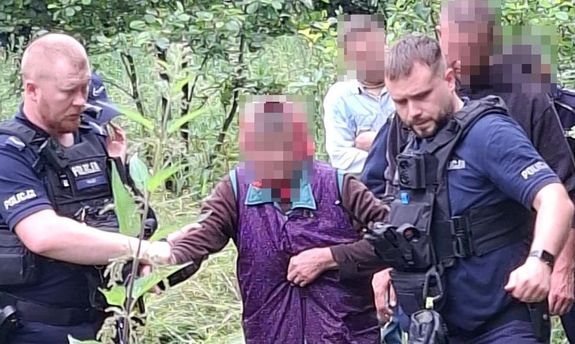 Policjanci prowadzą odnalezioną starszą panią.