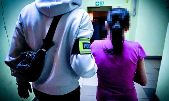policjant idzie z zatrzymaną.