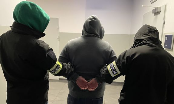 Dwaj policjanci prowadzą zatrzymanego.