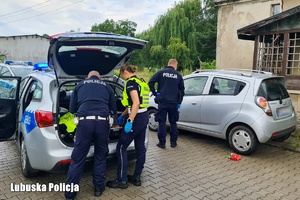 Troje policjantów przy radiowozie i i aucie cywilnym.