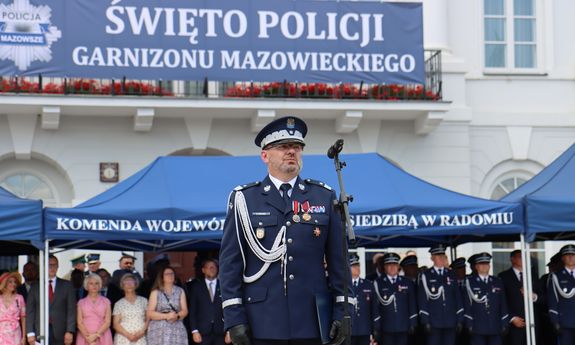 Komendant wojewódzki stoi na podeście. za nim jest napis święto policji w garnizonie mazowieckim.