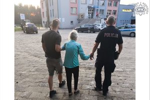 Policjanci prowadzą seniorkę.