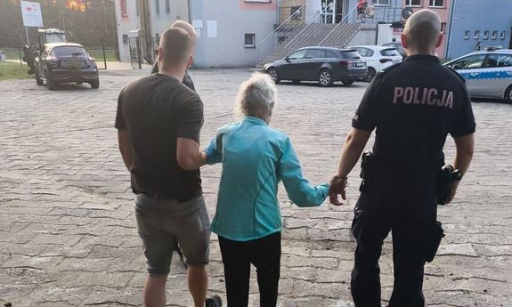 Policjanci prowadzą seniorkę.