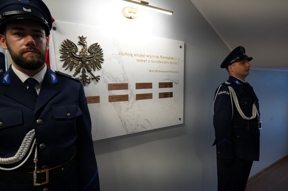 Dwaj umundurowani policjanci pełniący wartę przy tablicy z nazwiskami poległych policjantów.
